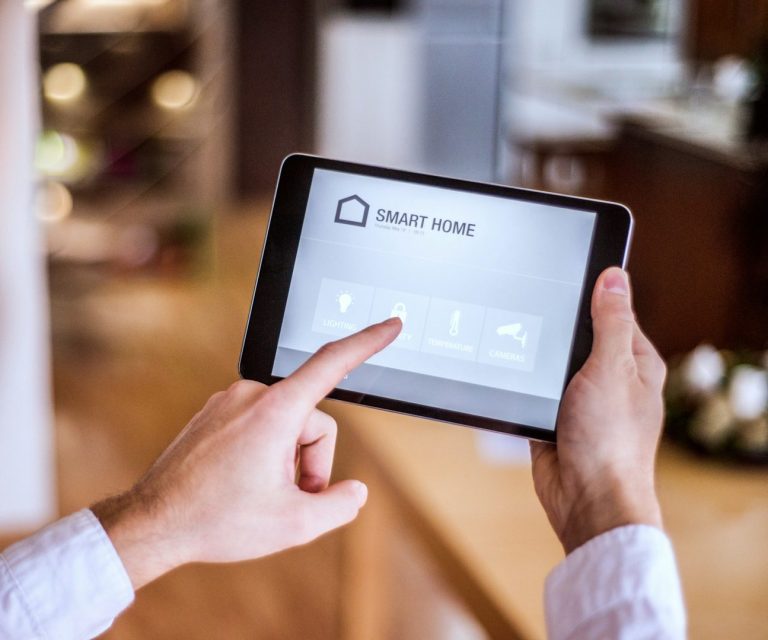 Person tippt auf ein Tablet mit einer Smart-Home-Oberfläche.