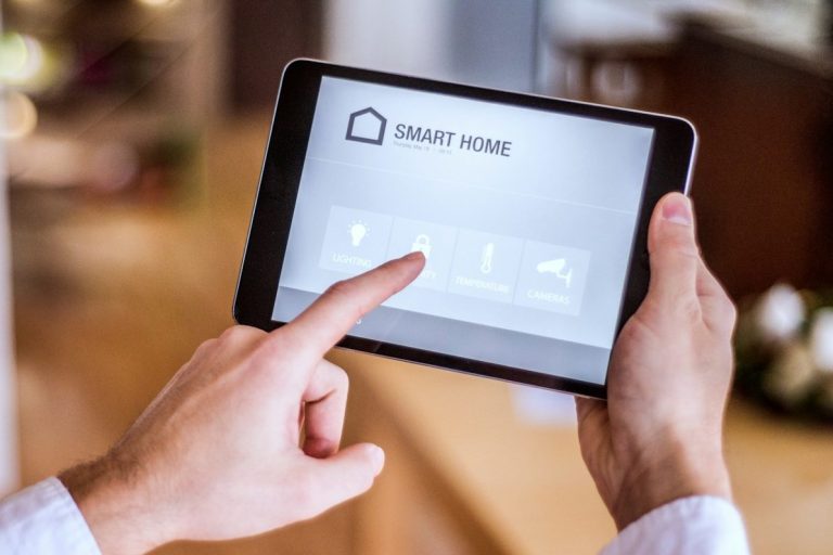 Hand, die auf ein Tablet mit Smart-Home-Steuerung tippt.