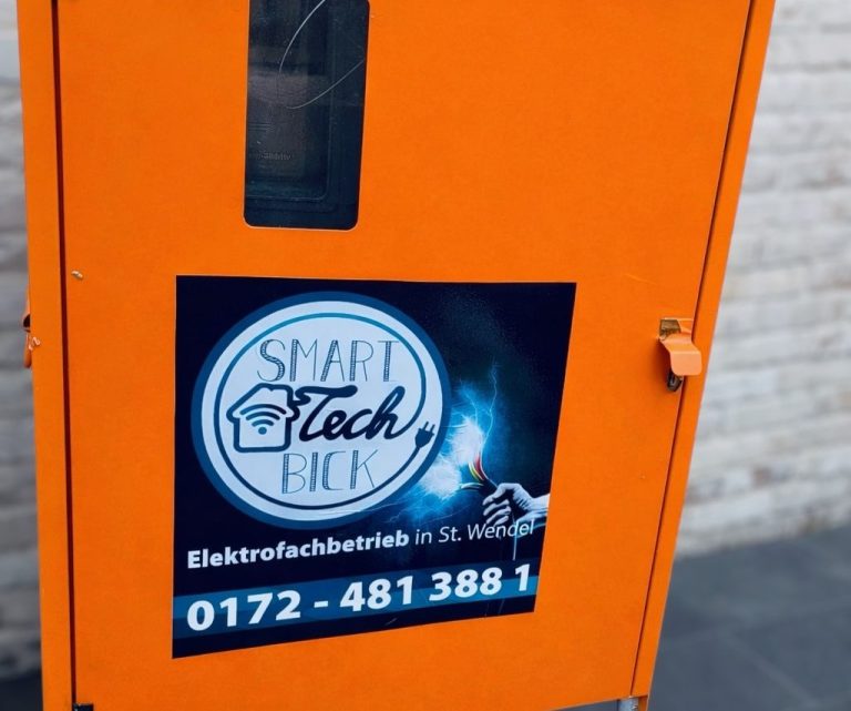 Orange farbener Baustromverteiler-Kasten mit Werbeaufkleber für Smart Tech Bick, Kontaktdaten und Dienstleistungen.