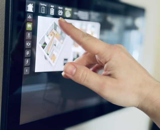 Eine Hand tippt auf einen Touchscreen mit einem interaktiven Grundriss.