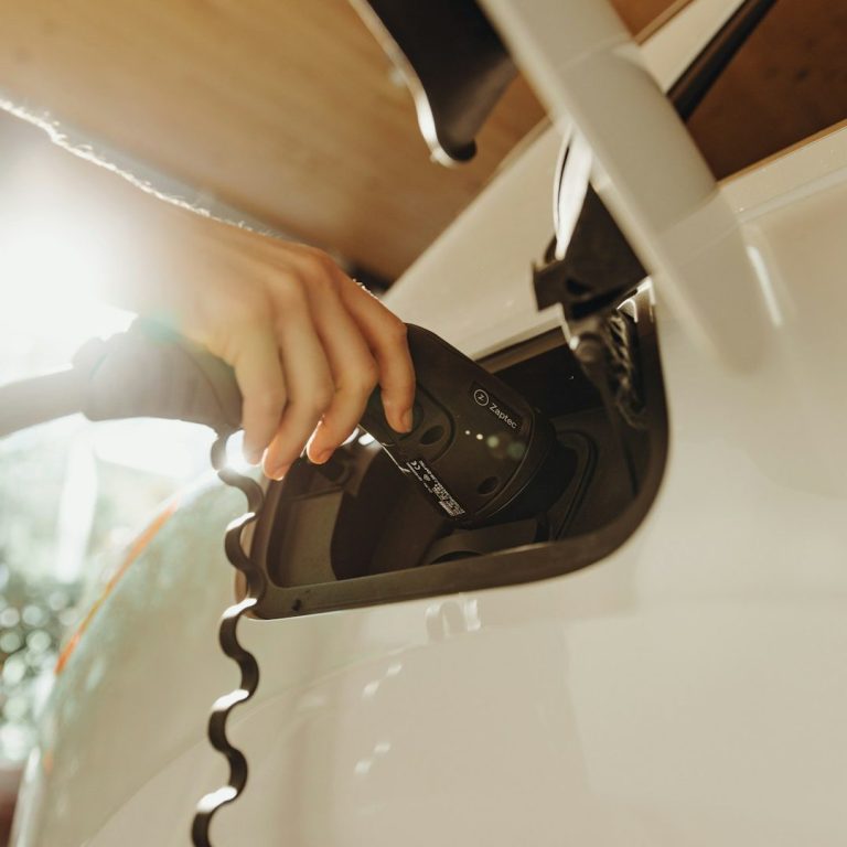 E-Ladestation Eine Hand verbindet ein Ladekabel mit einem Elektroauto.