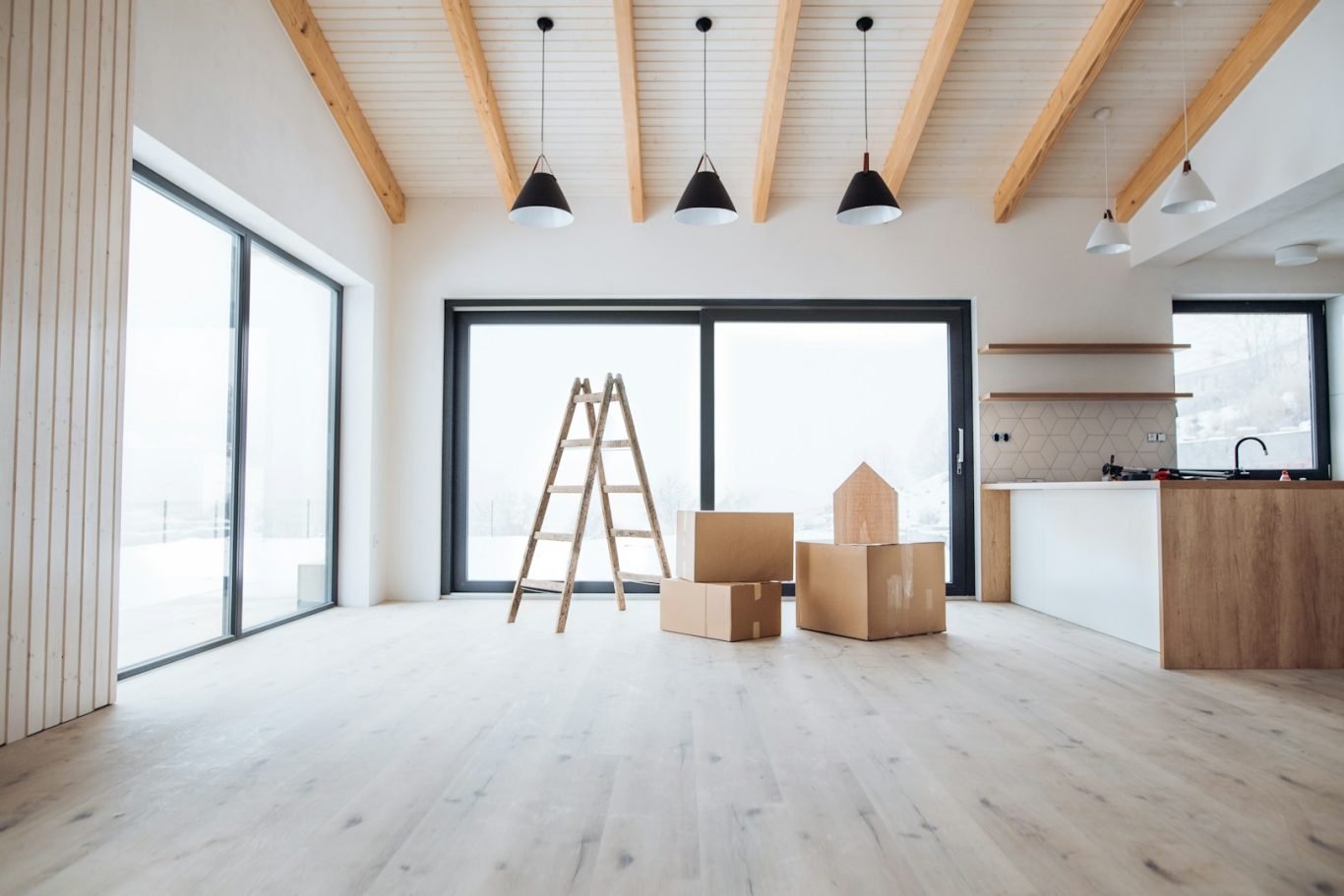 Elektroinstallation Neubau Helle Innenansicht mit Holzdecke, Leiter und Umzugskartons im offenen Raum.