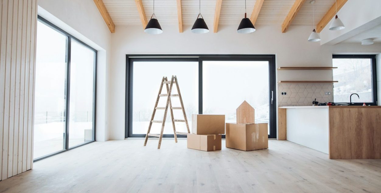Elektroinstallation im Neubau Heller Innenraum mit Holzleitern, Kisten und großen Fenstern.