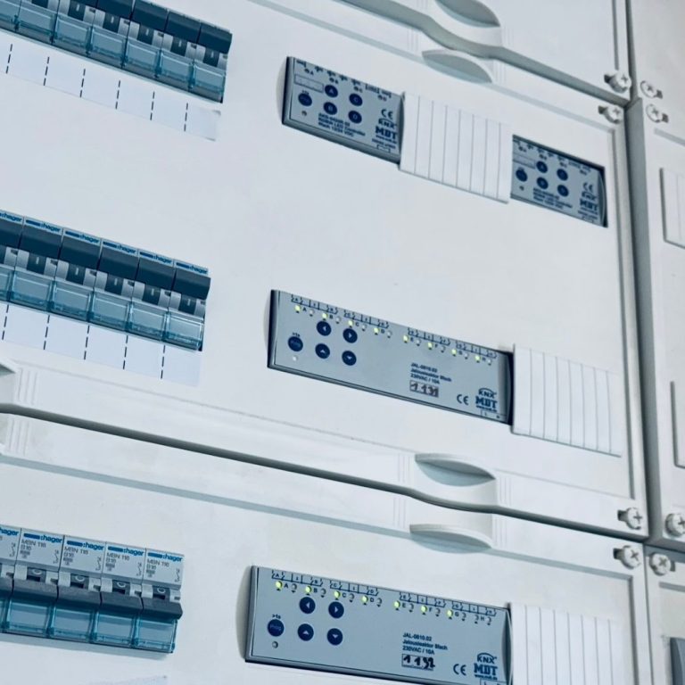 Zählerschrank Schaltkasten mit grauen und blauen Steuergeräten und Beschriftungen.
