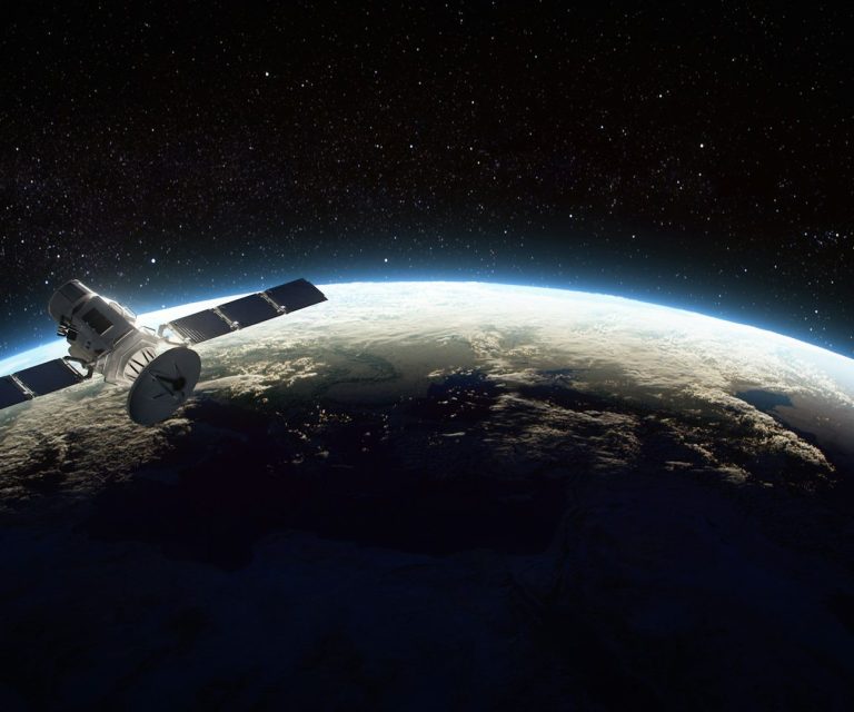 Ein Satellit schwebt über der Erde im Weltraum, umgeben von Sternen.
